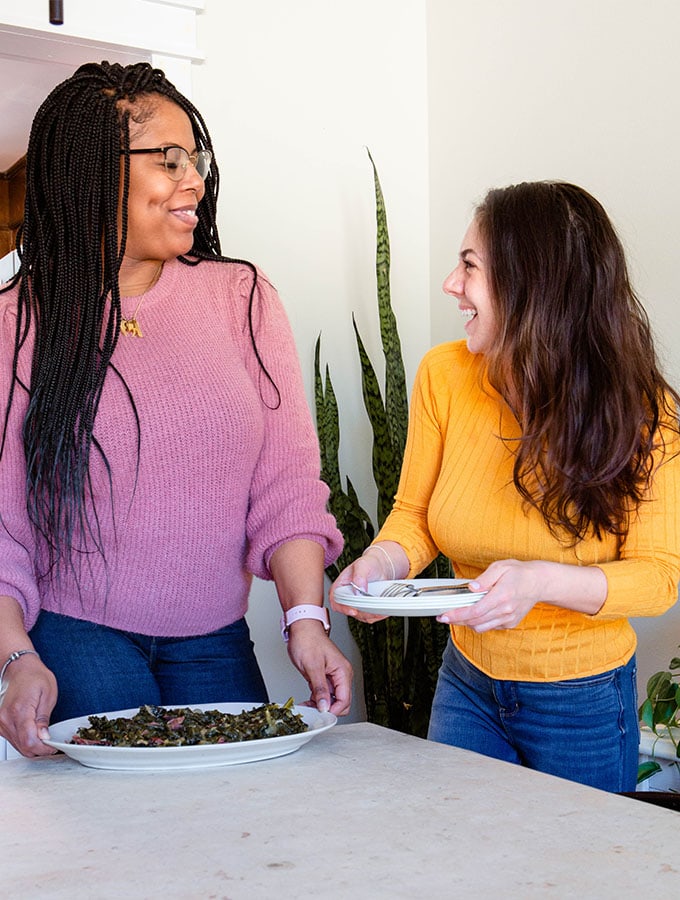 Sherry and Kyla are holding a plate of collard greens and smiling.