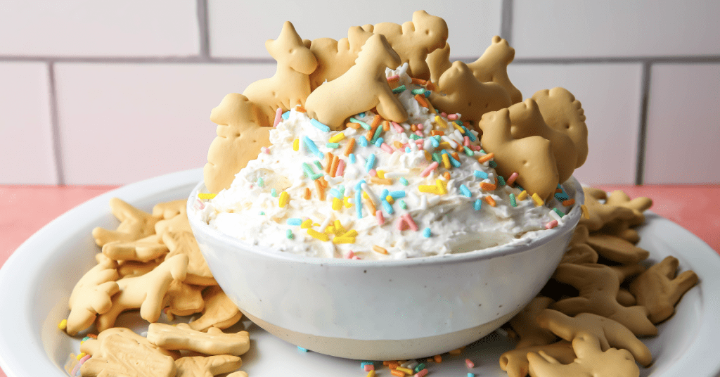 Animal crackers are placed in the dip and topped with sprinkles.