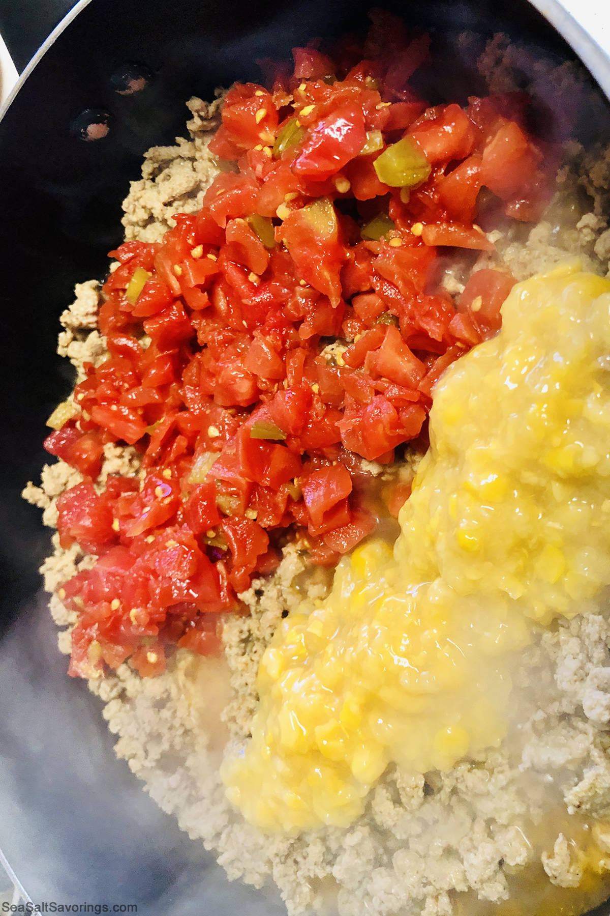 ground beef and tomatoes and creamed corn in a skillet cooking