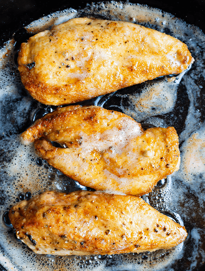 chicken breasts cooking in frying pan