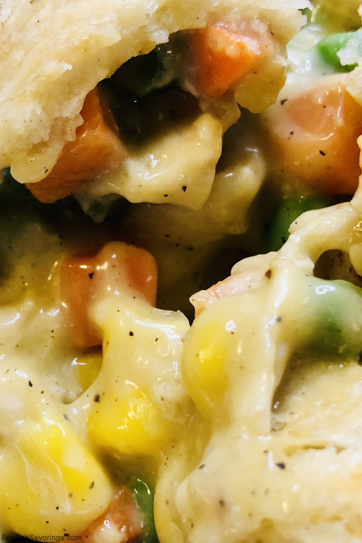 close up view of a scoop of chicken pot pie showcasing the textures of the sauce and filling