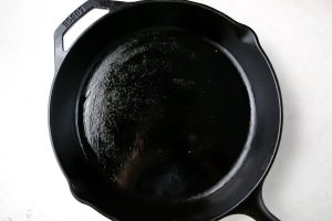 A cast iron pan is greased and prepared for cooking.
