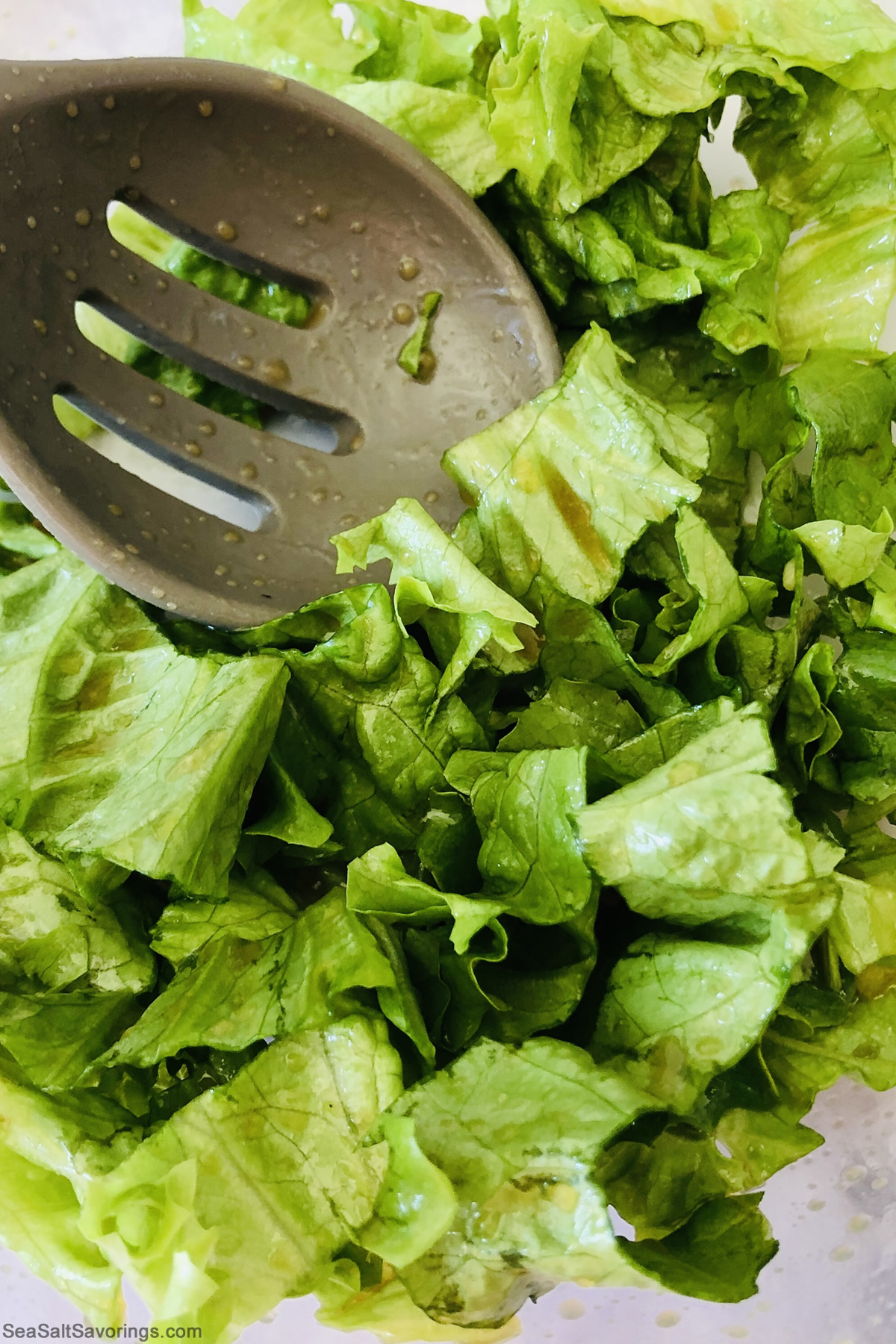 mixing lettuce and dressing together in a bowl