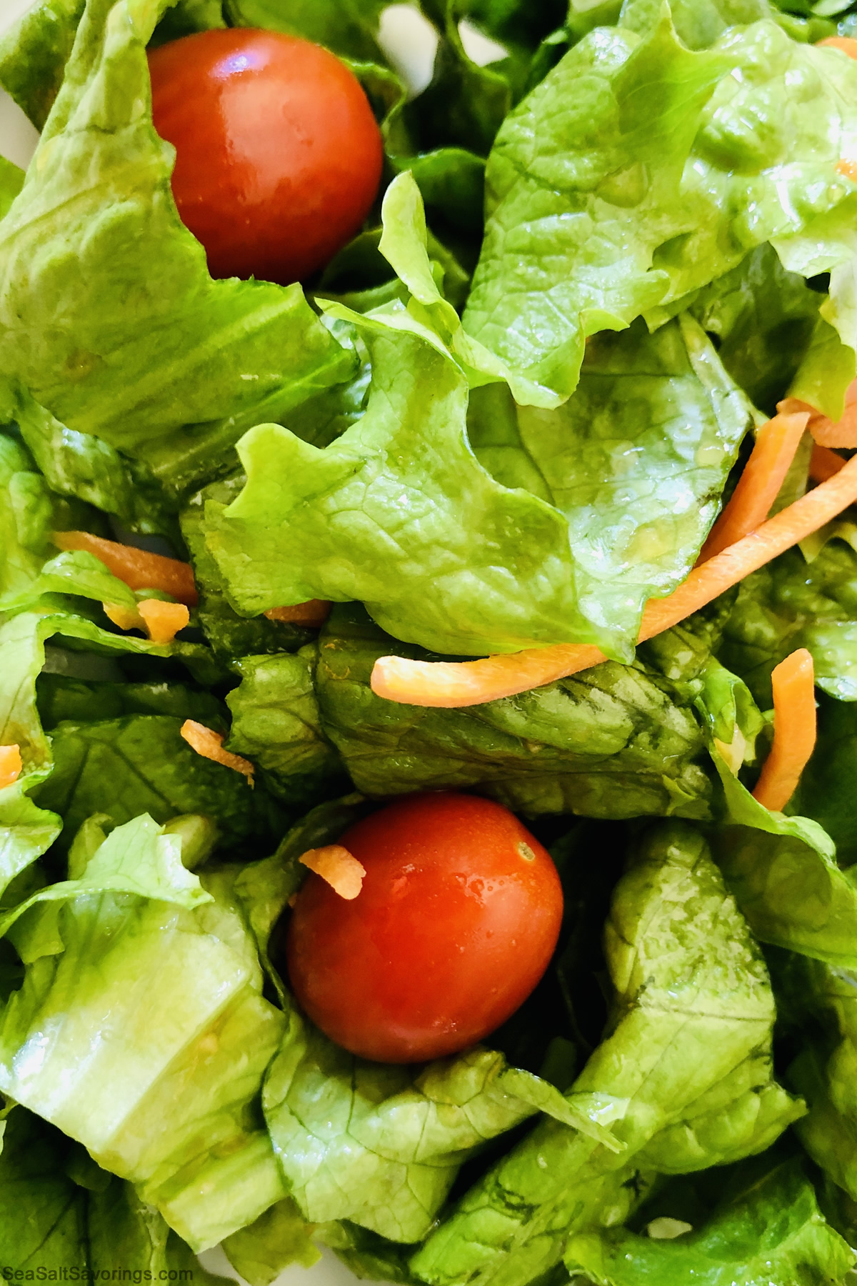 close up view of fresh lettuce and carrot strips and tomatoes