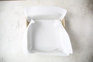 Parchment paper is used to line the 9X9 baking dish before the crust is placed in it.