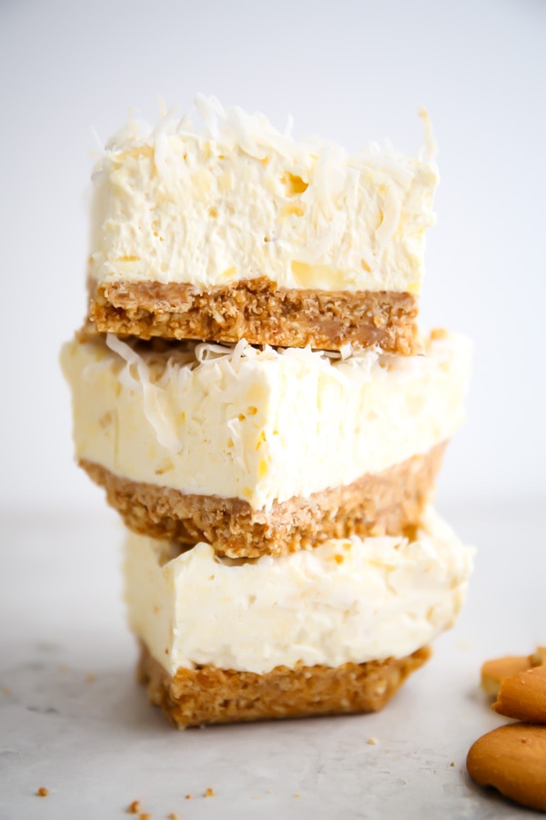Cheesecake bars are stacked next to vanilla wafers.