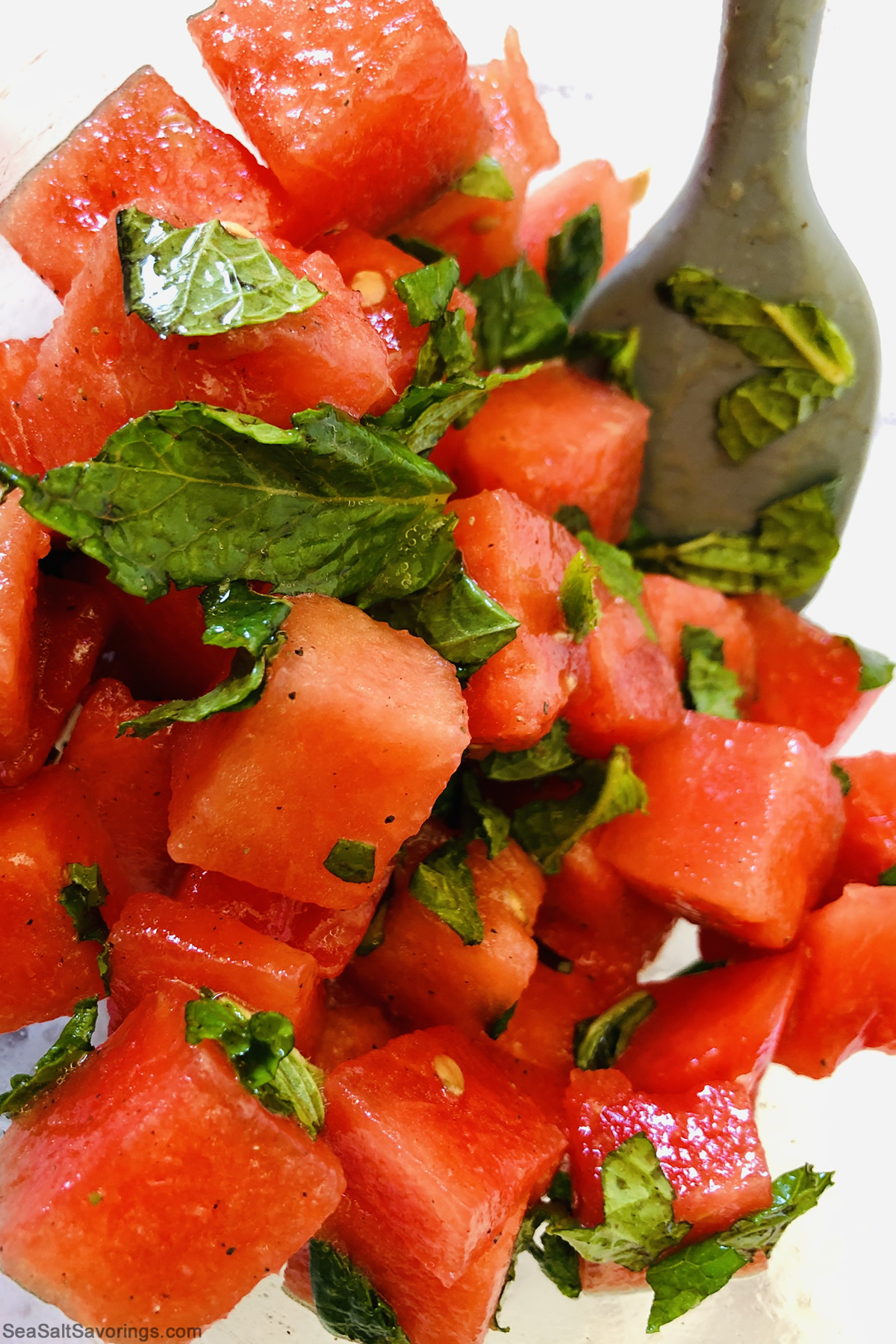 stirring watermelon and chopped mint leaves