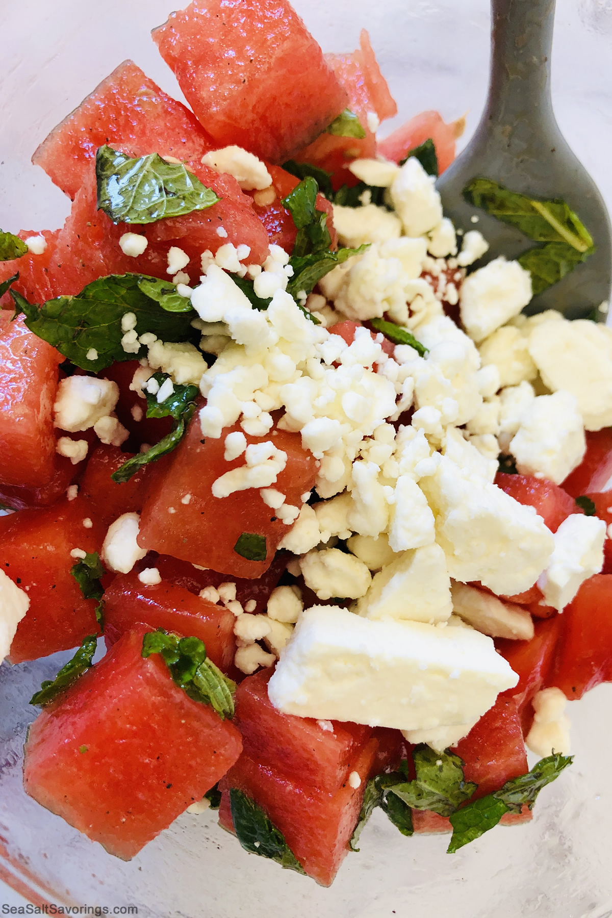 adding feta to watermelon and mint leaves to mix