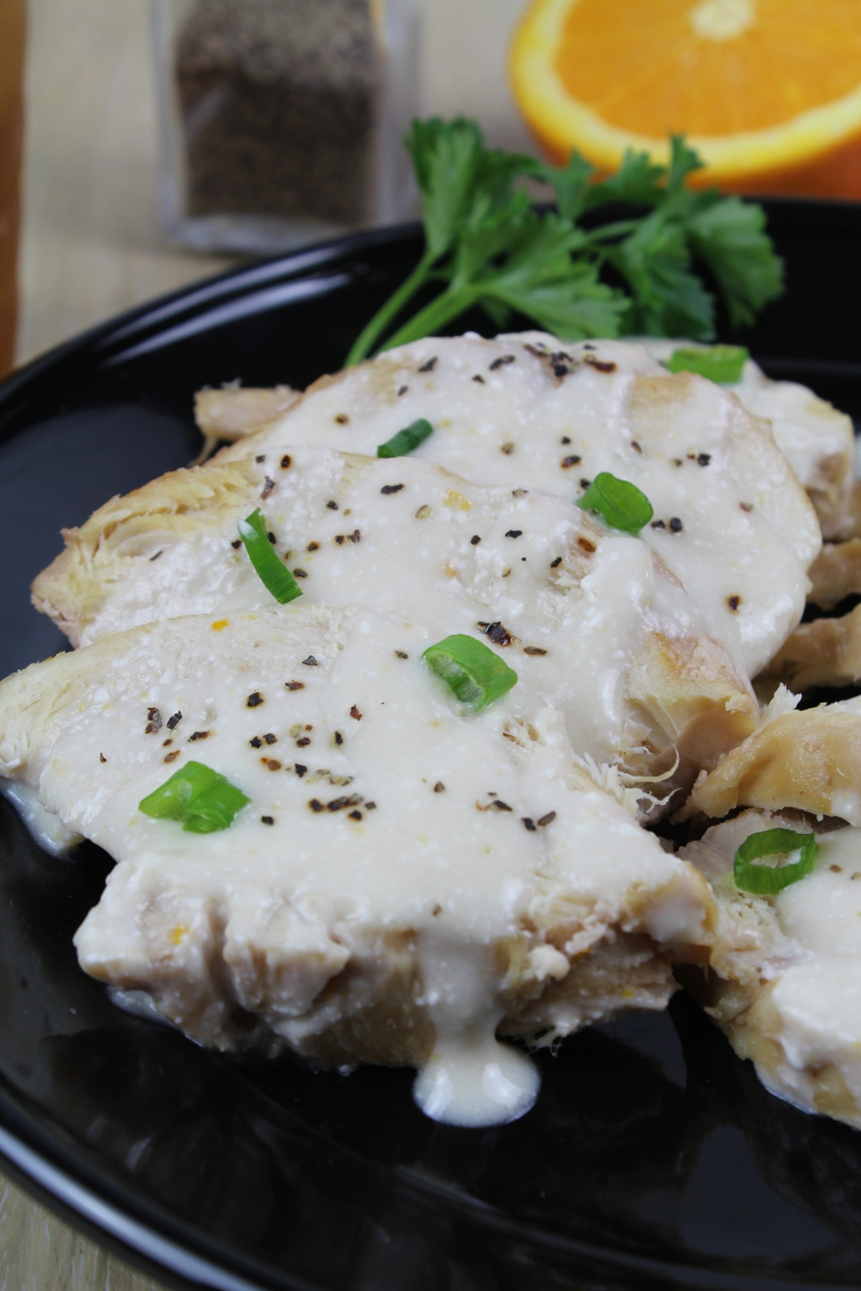 close up view of a orange chicken breast with orange sauce on top