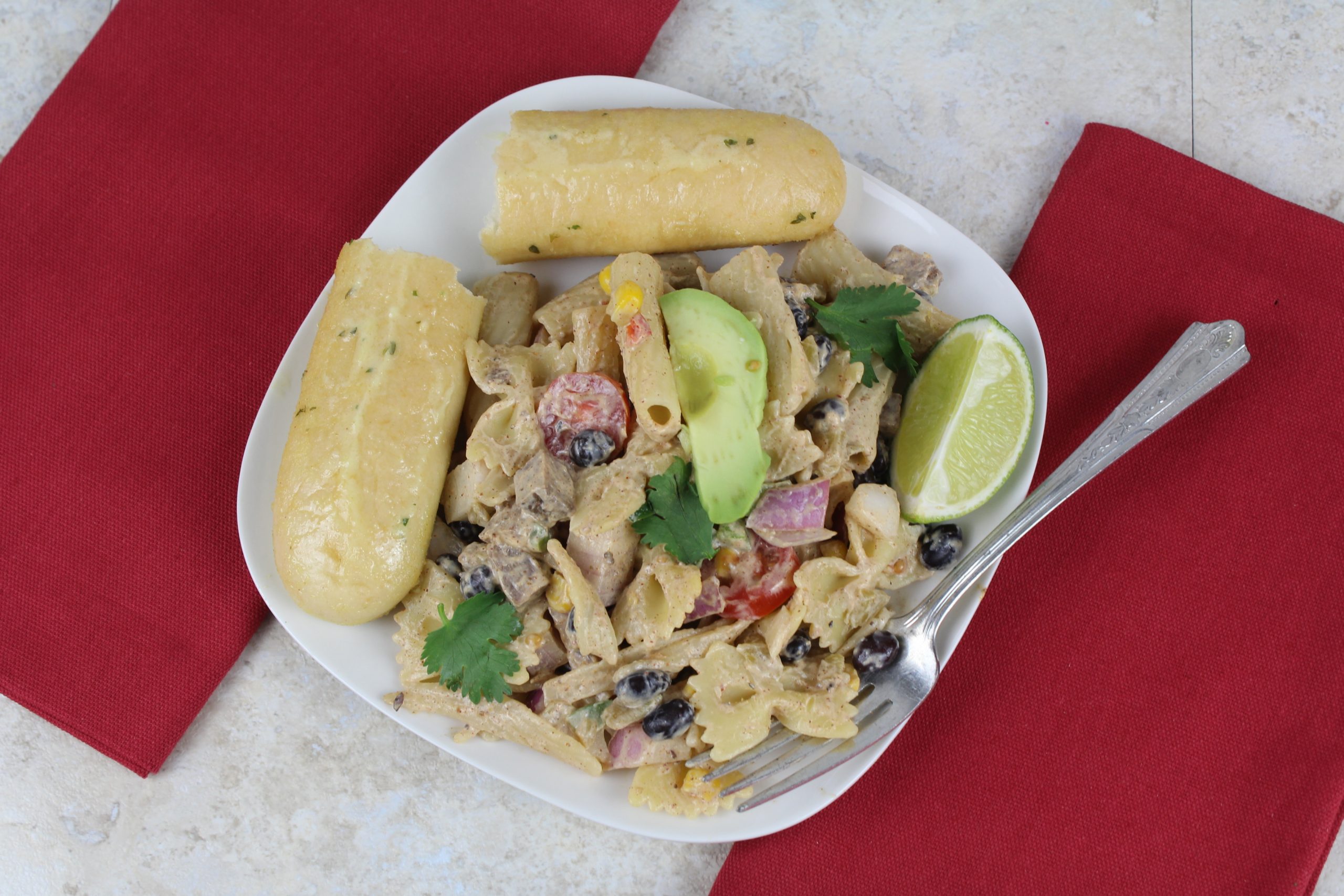 overhead view of steak salad on a plate with breadstick and lime wedge garnish