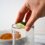 A lime is glided around the edge of a glass so the salt will stick to the rim.