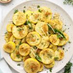The summer squash is roasted, then plated on a white plate and topped with parsley.