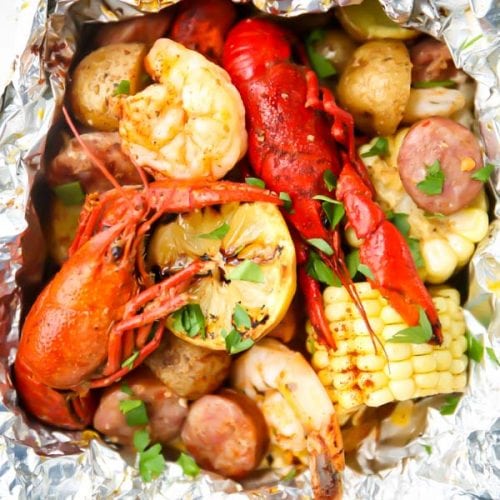 Crawfish, lemons, corn, potatoes, and sausage are cooked in a foil packet and topped with parsley.