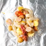 Shrimp, crawfish, sausage, corn, and potatoes are placed on the grilling foil before they are wrapped.