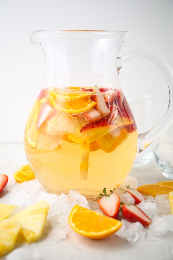 glass pitcher full of sangria drink and cut fruit