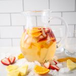 The sangria pitcher is full of fruits, rum, and wine.