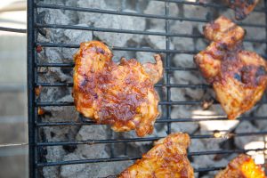 The chicken thighs are placed on the grilled and layered in BBQ sauce.