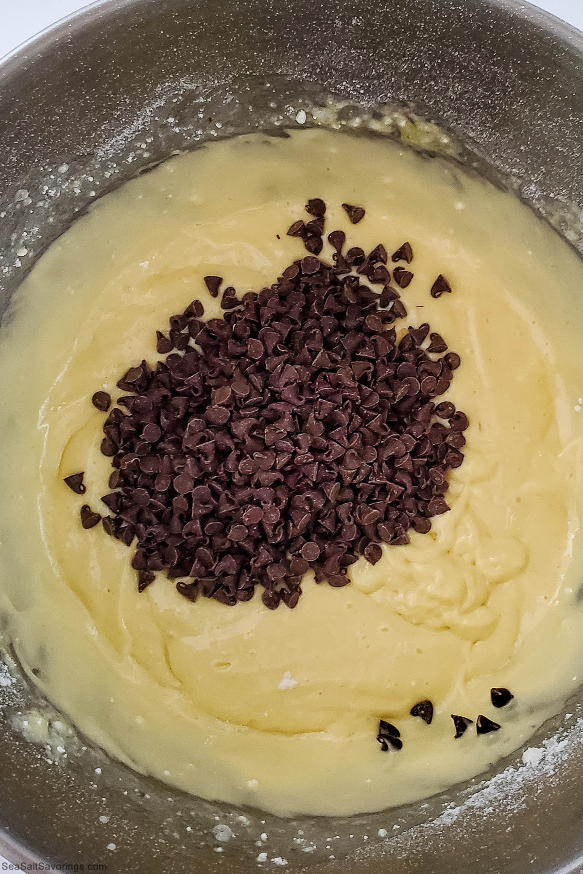 batter for cupcakes in a mixing bowl with chocolate chips dumped on top