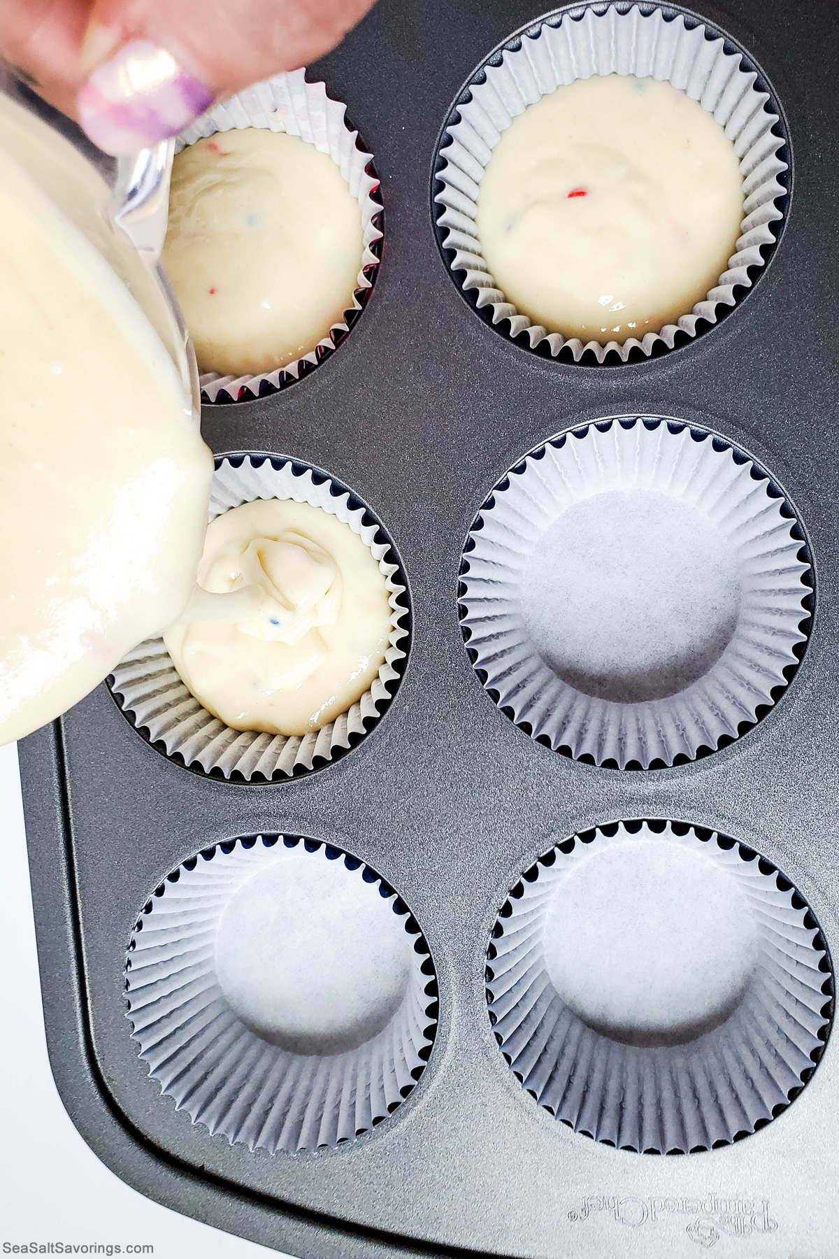 pouring batter into cupcake pan lined with cupcake papers