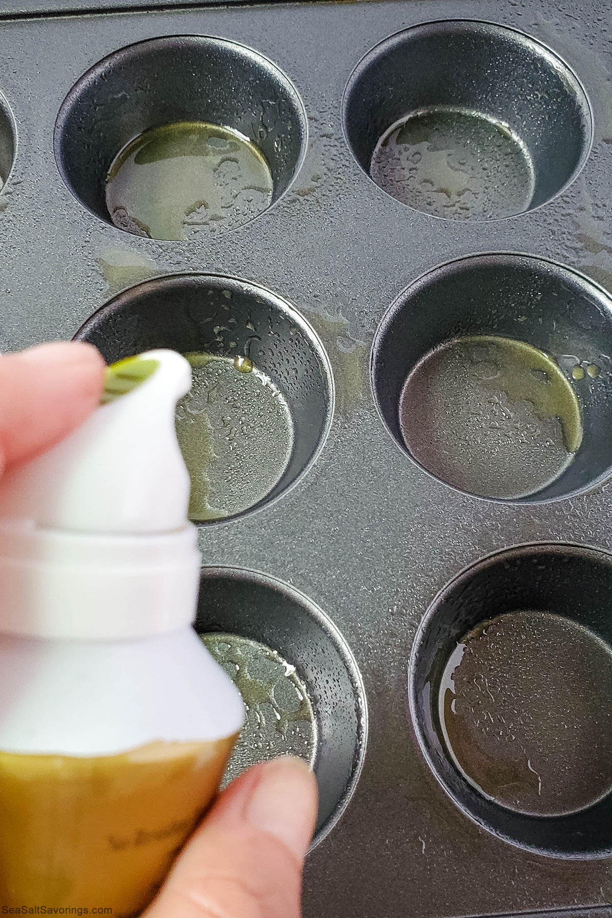 spraying oil in cupcake baking dish