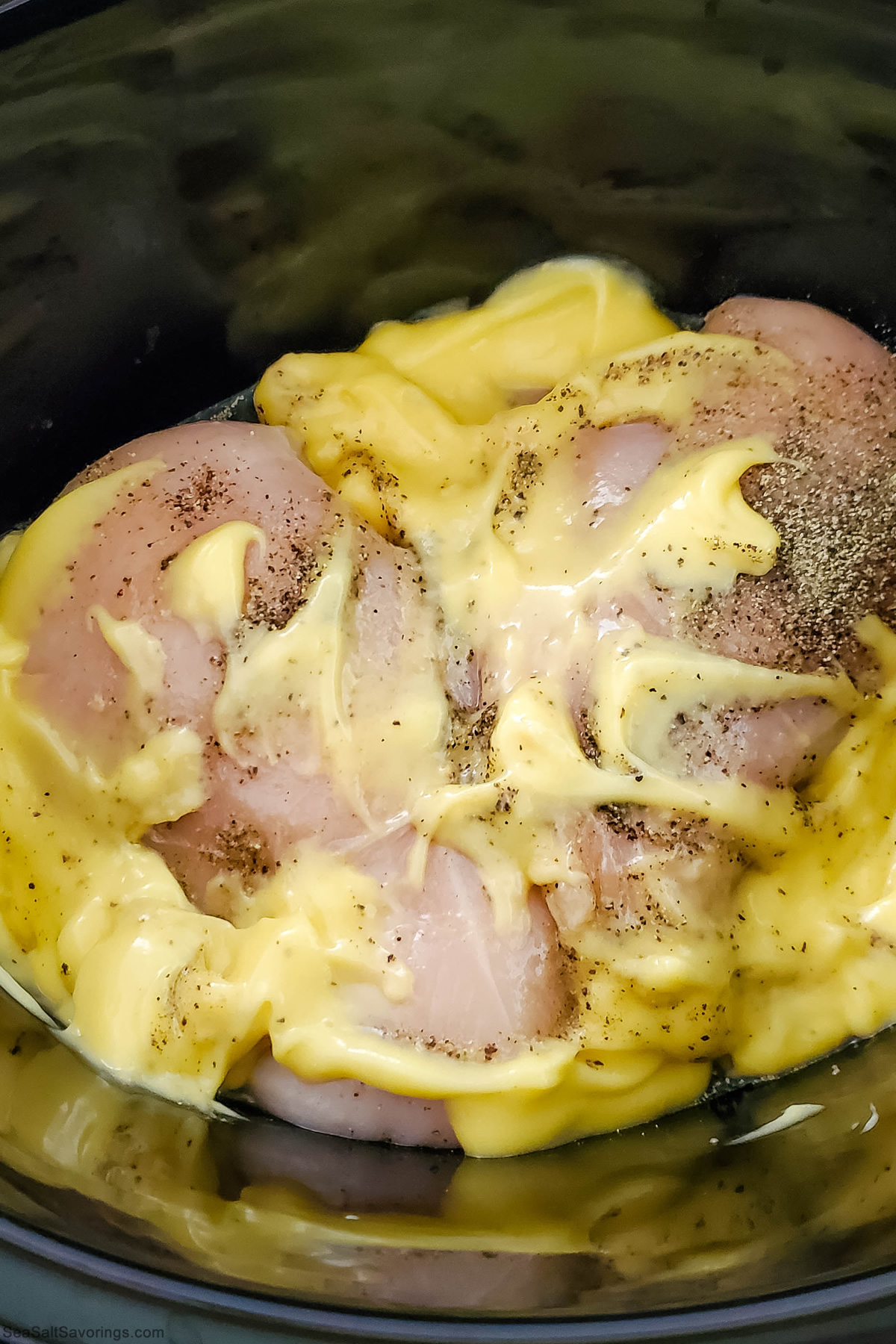 inside a crock pot showing the chicken covered in sauce