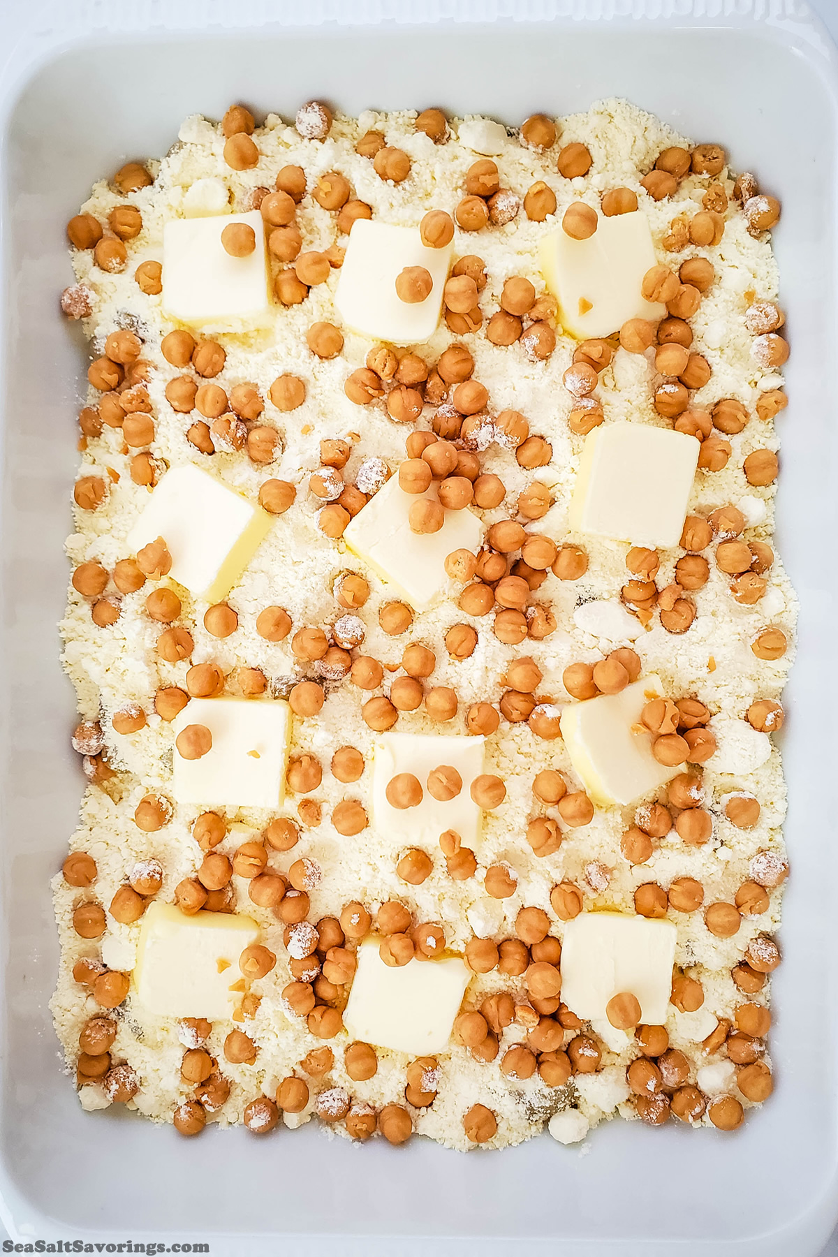 baking dish with apples and dry ingredients and butter dumped in layers