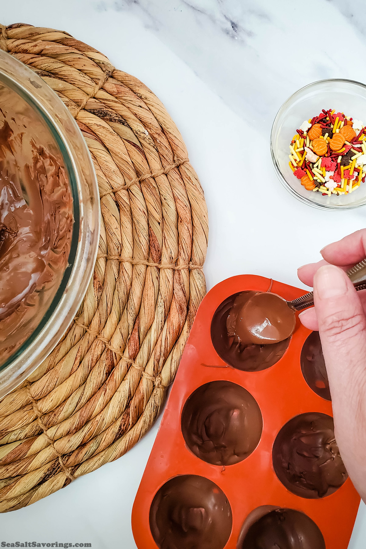 using a spoon to coat the edges of a mold to make halves of chocolate ball