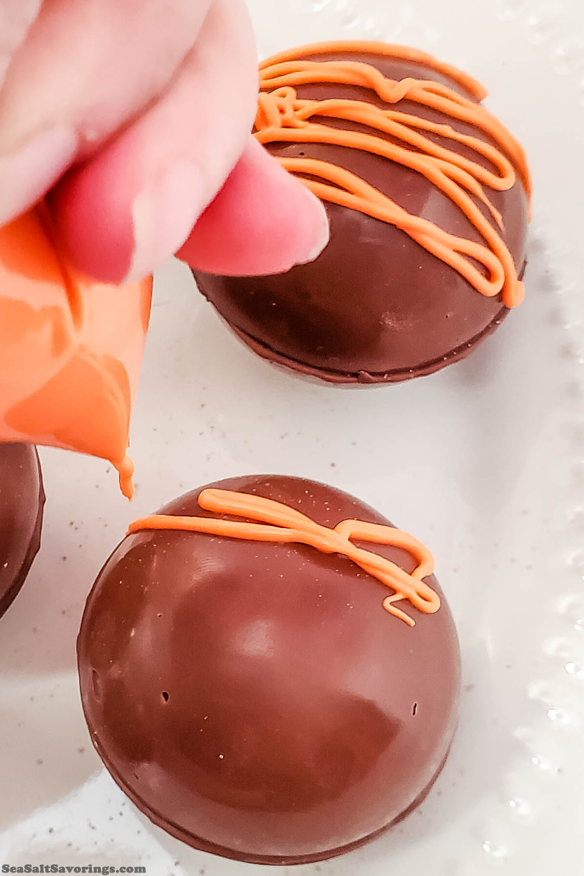 using a piping bag to squirt frosting on top of cocoa bombs