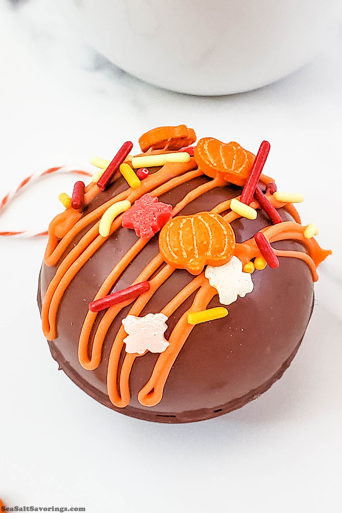 a cocoa bomb decorated with fall colored sprinkles