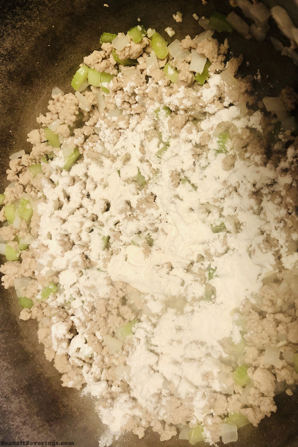 adding flour to beef and vegetables base