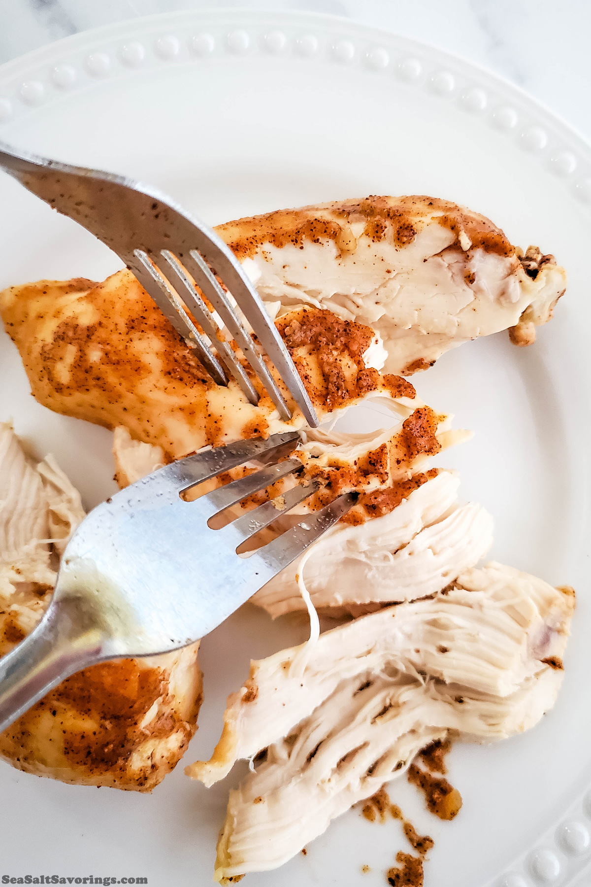 chicken pieces placed on a plate and shredded with forks