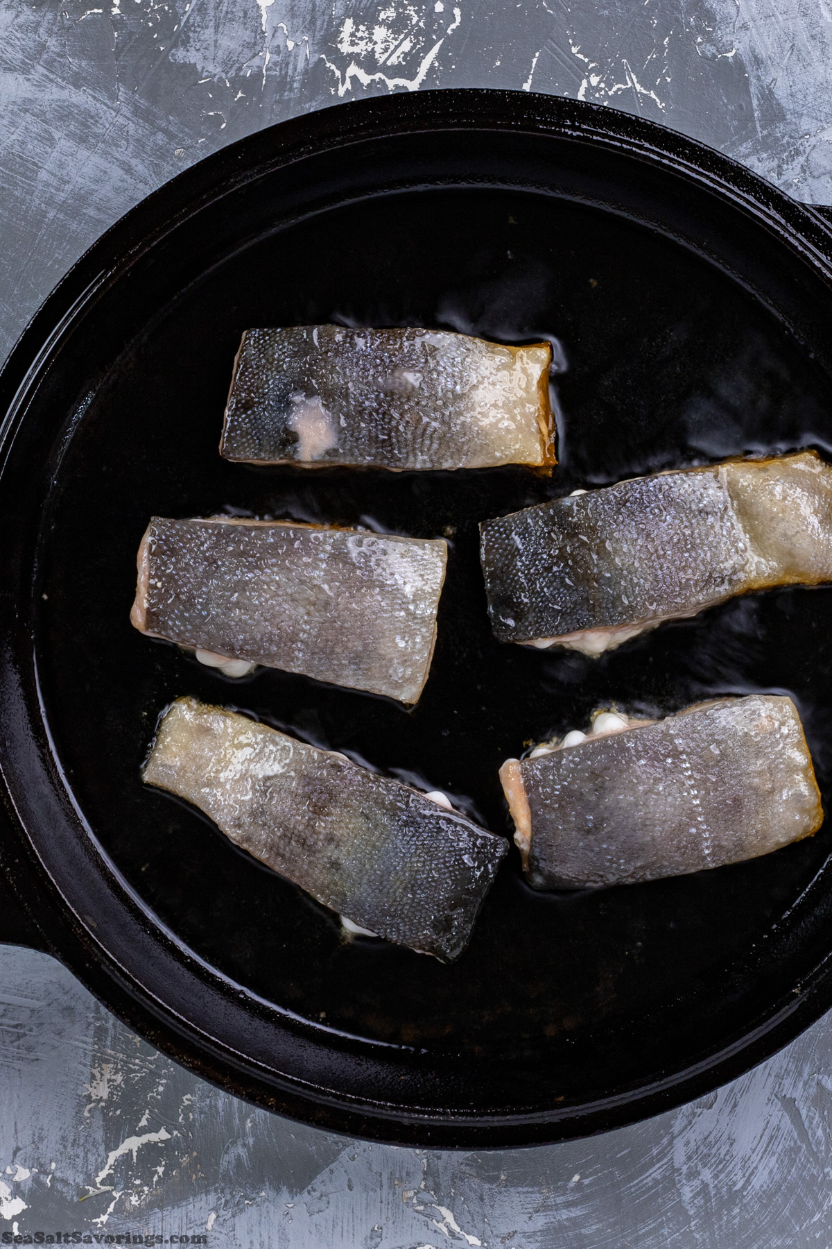 placing salmon filets in frying pan to cook