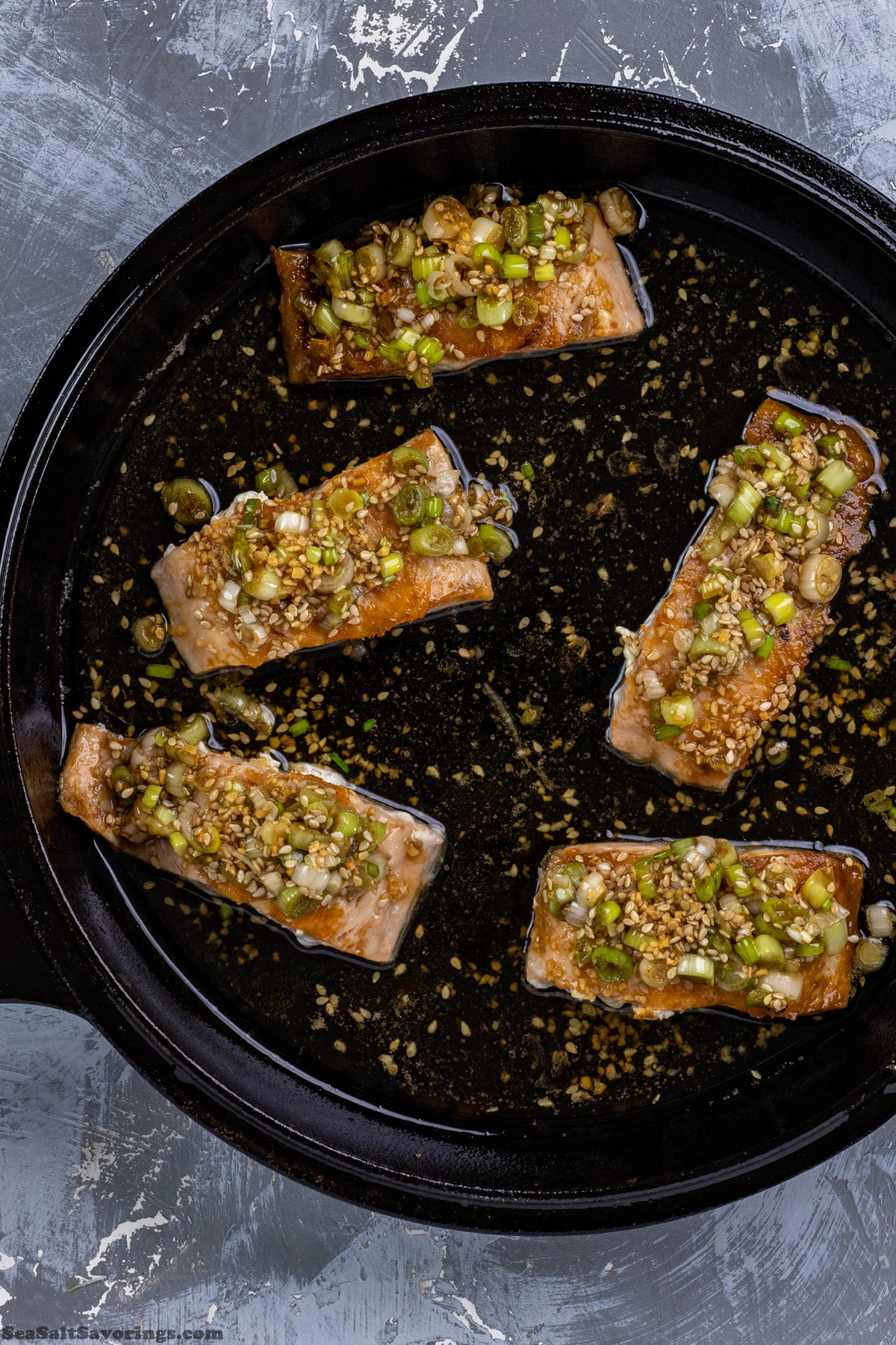 adding sauce glaze on top of filets as they cook in pan