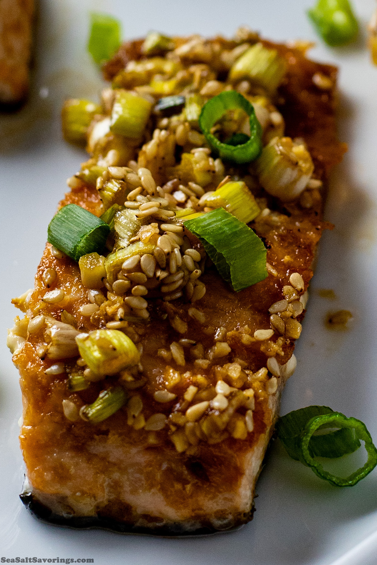 close up view of a salmon filet cooked and topped with a sesame sauce