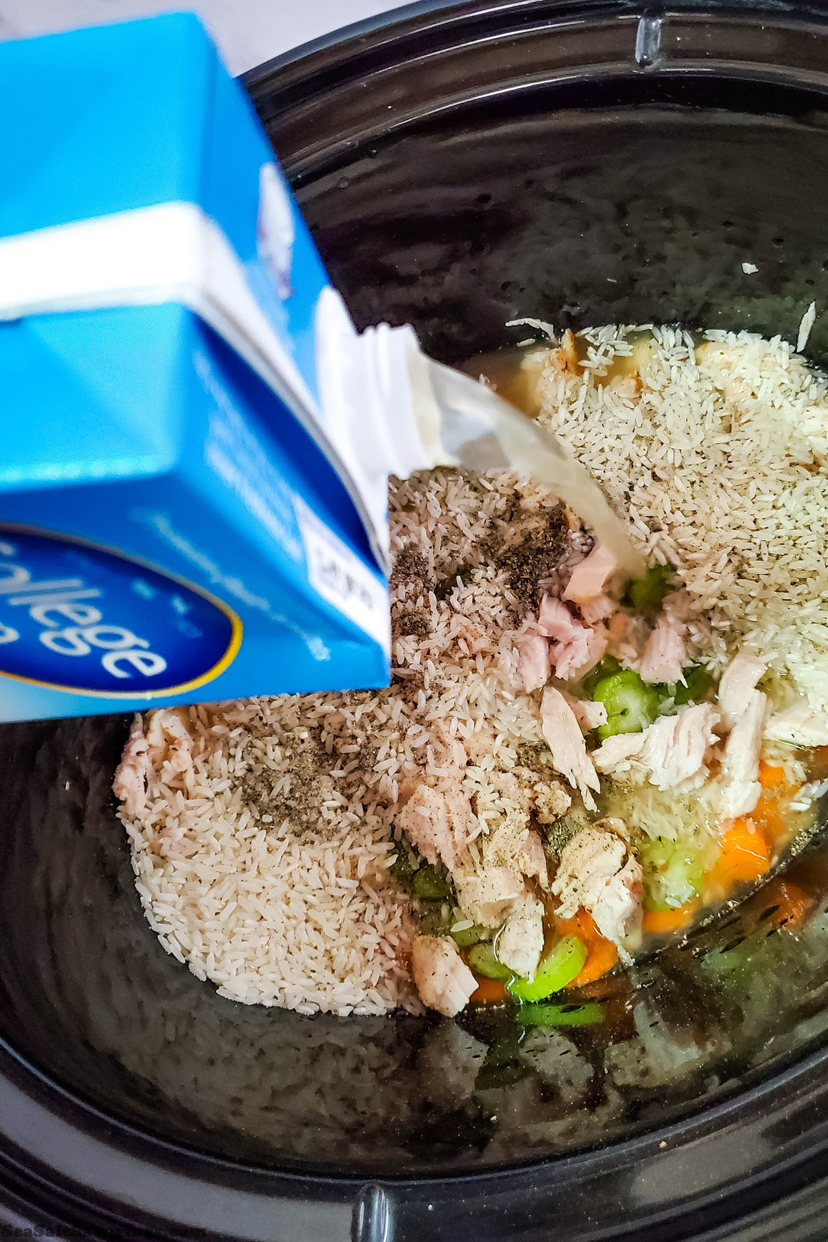 pouring broth into crock pot of soup ingredients