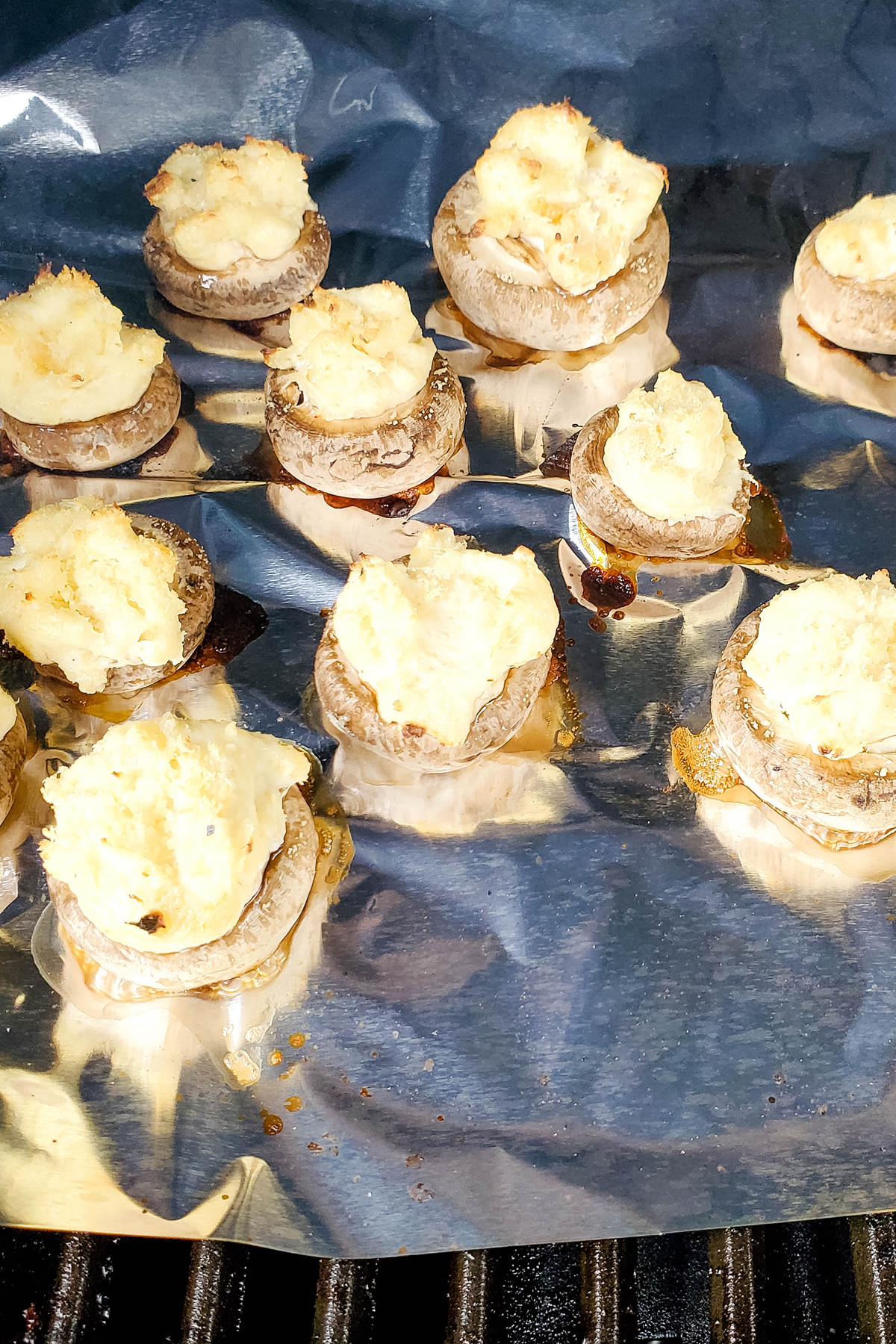 filled mushrooms on tin foil in a grill getting cooked