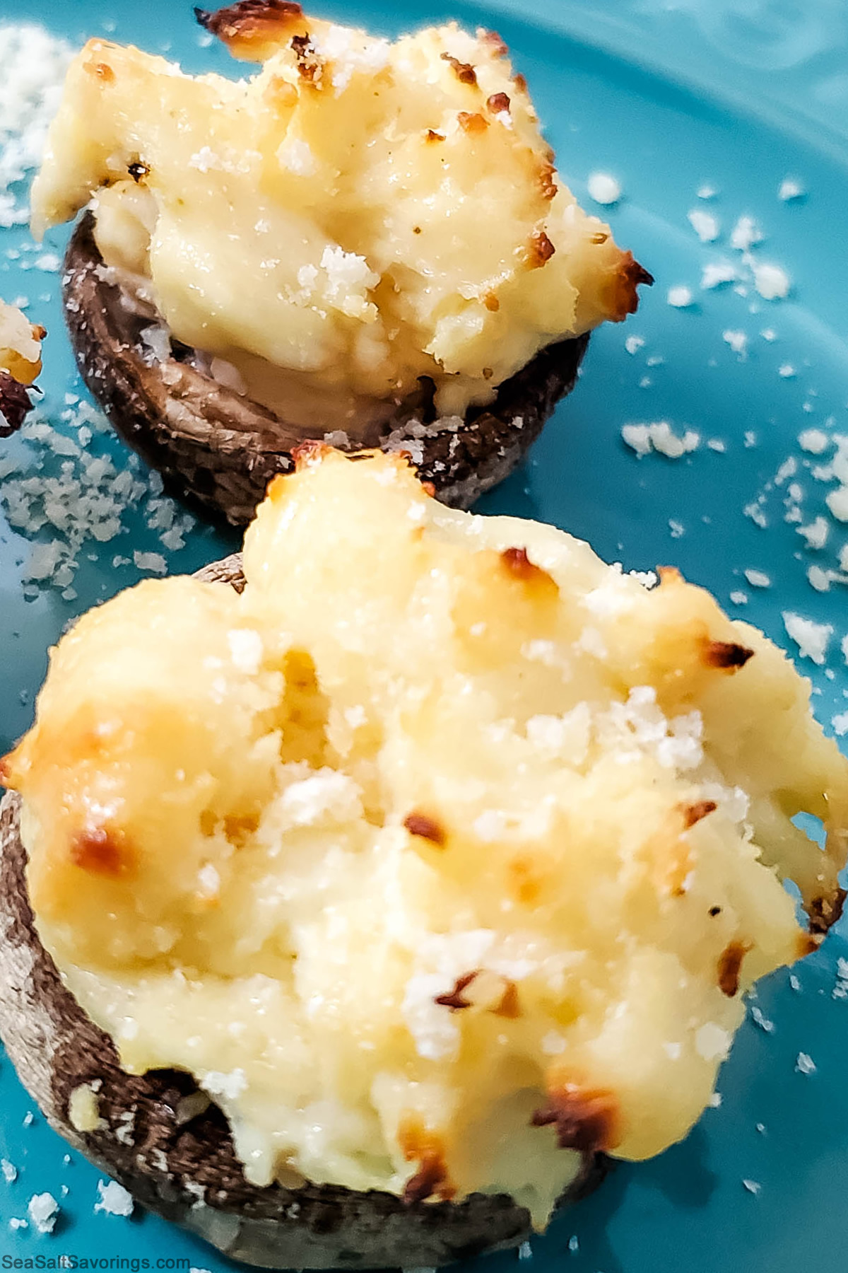 stuffed mushrooms on a blue plate sprinkled with parmesan flakes