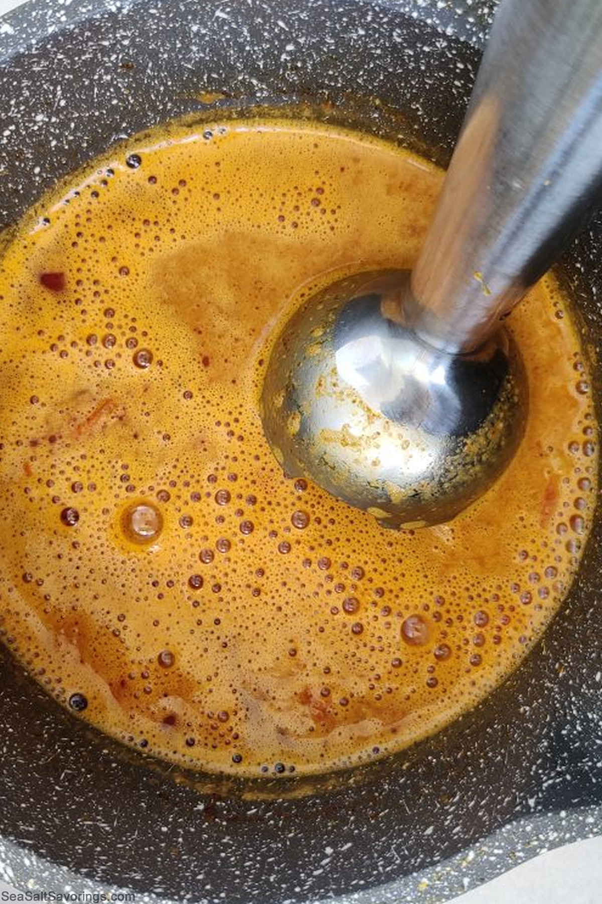 handheld mixer blending ingredients in bowl to make curry base