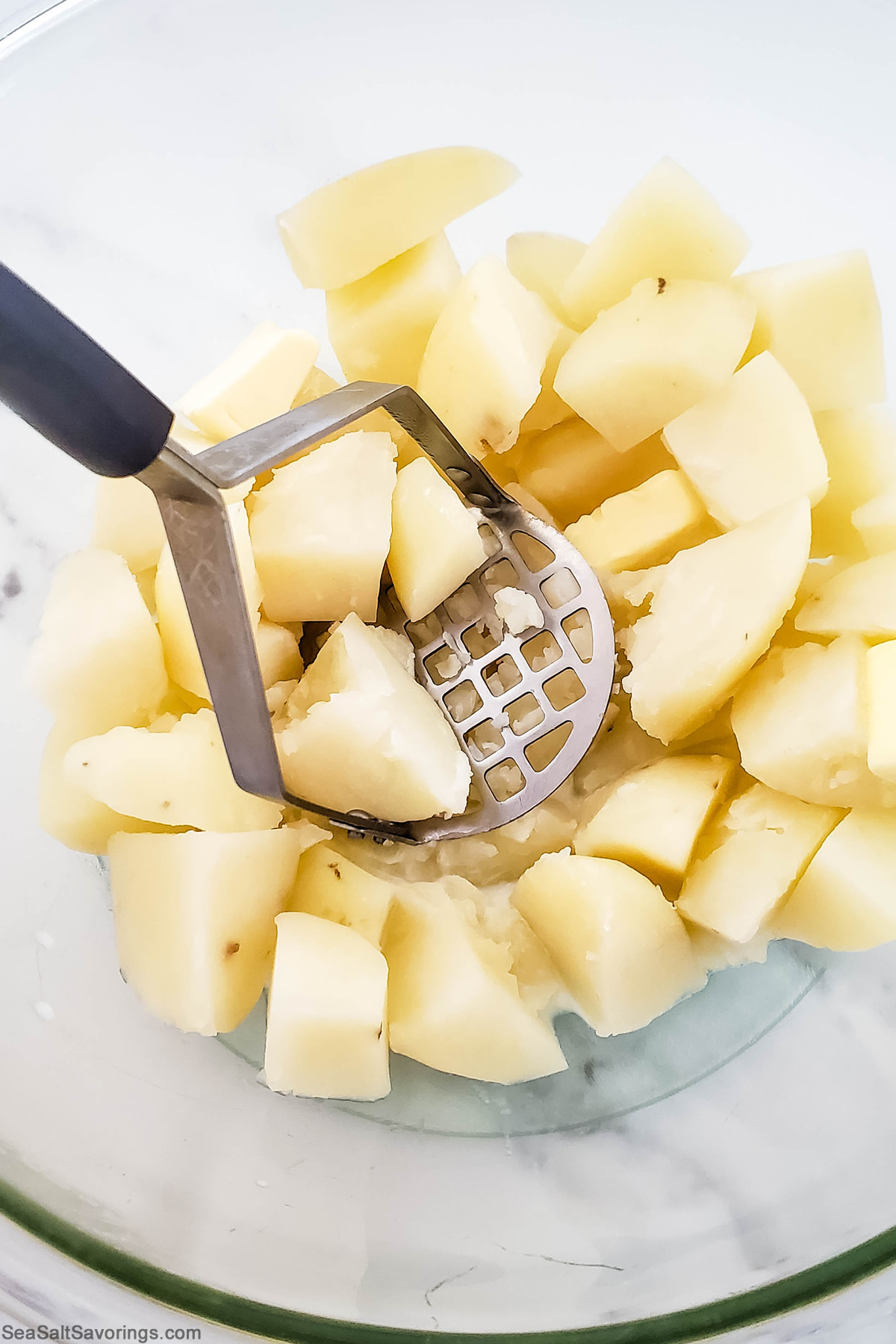 potato masher mashing potatoes in a bowl