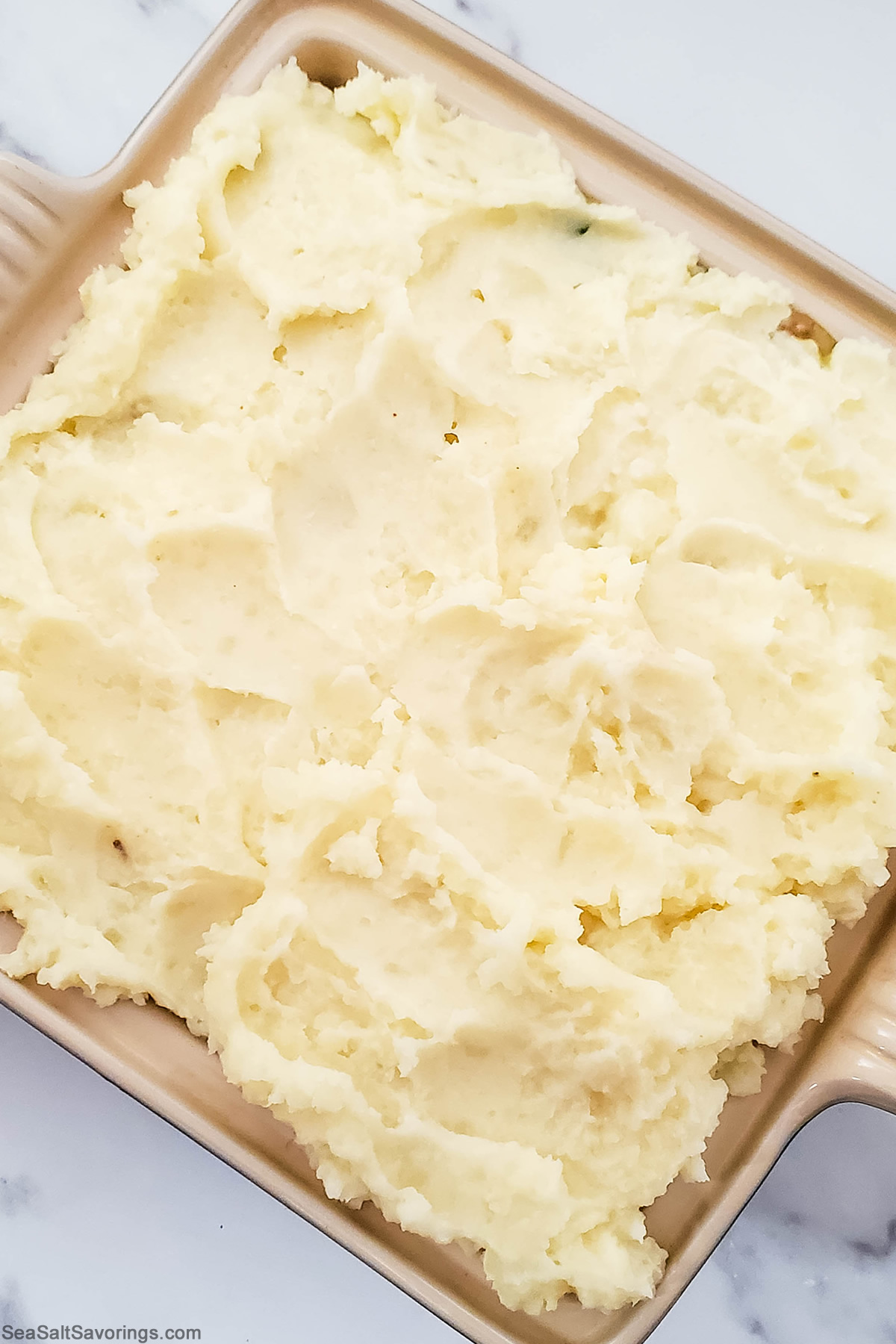 baking dish with mashed potatoes placed on top of filling