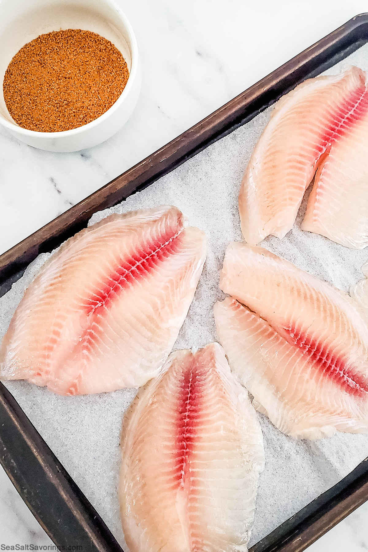 placing the fish on a baking sheet and then seasoning