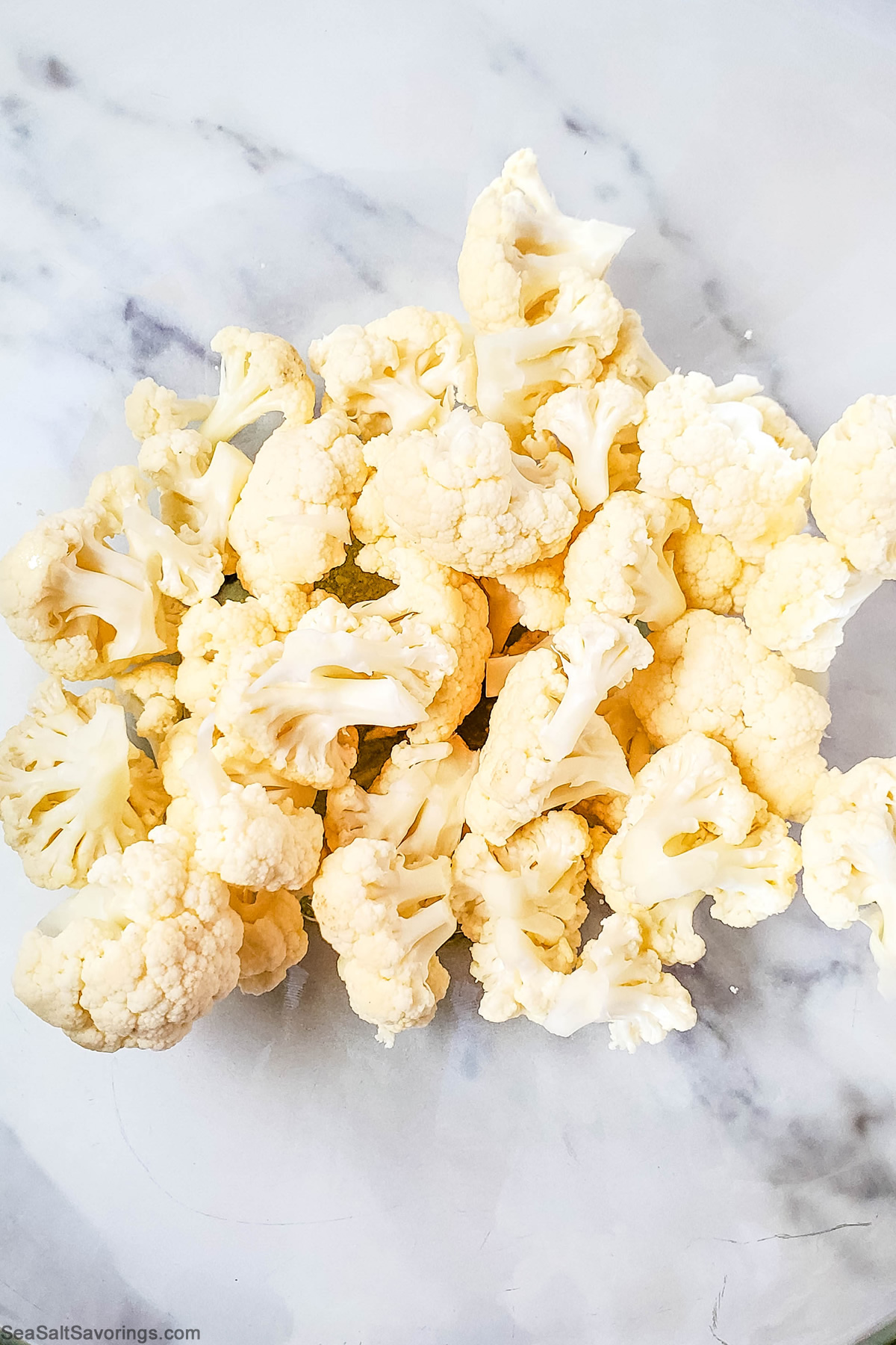 glass bowl full of cauliflower mixed with seasoning