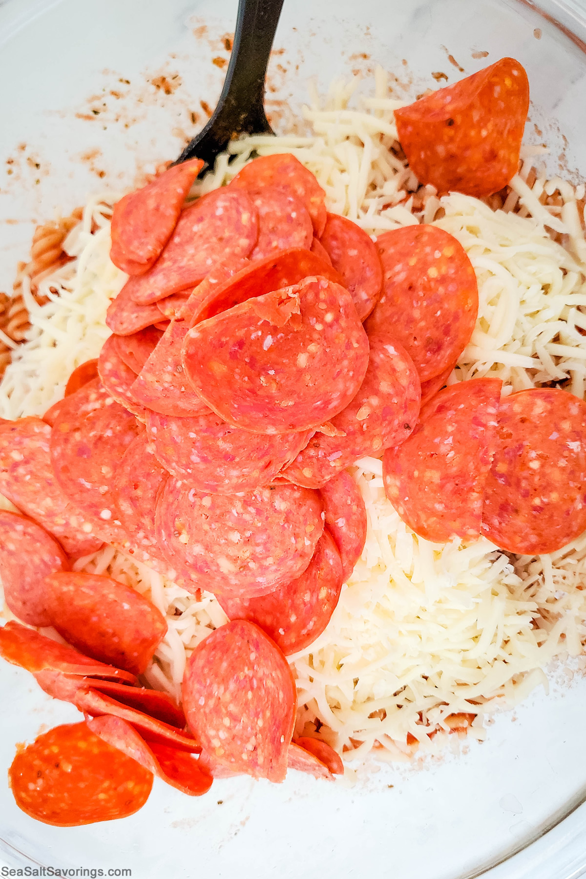 mixing bowl full of noodles and sauce and cheese and pepperoni