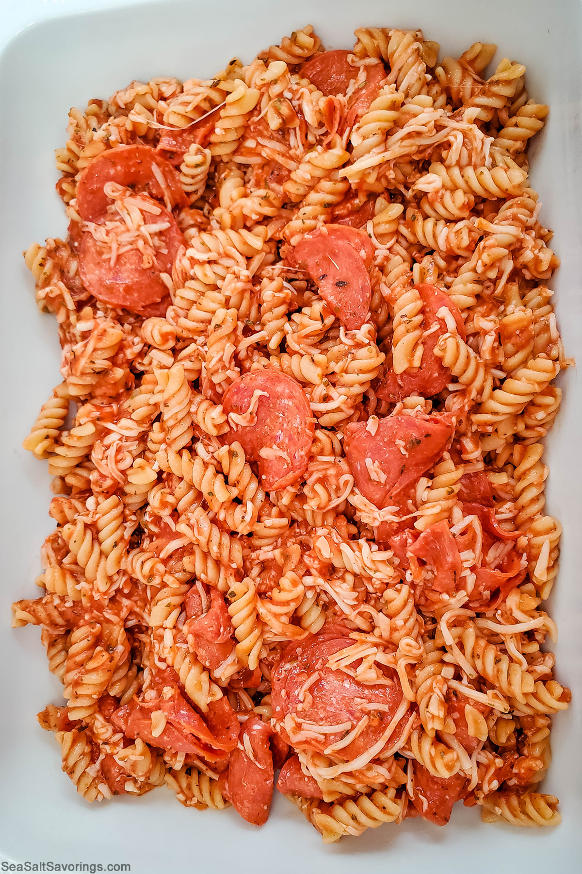 baking dish with noodle and sauce and pepperoni mixture