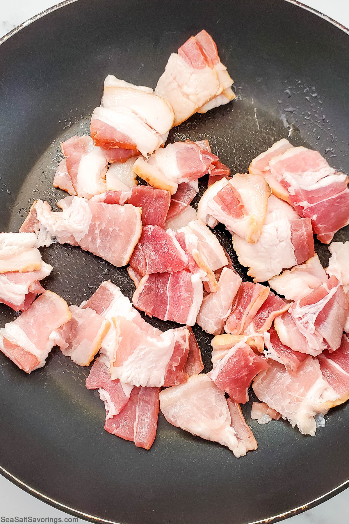 bacon chunks cooking in a skillet