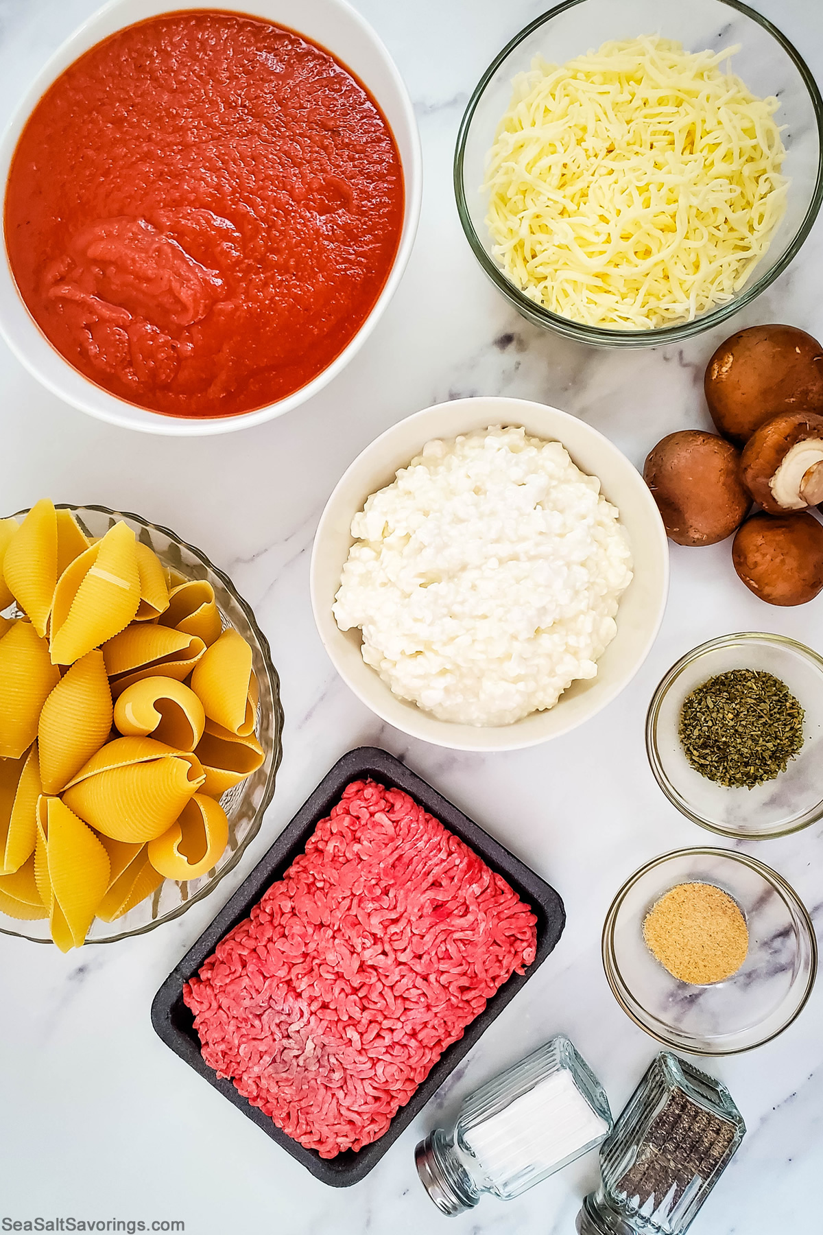 ingredients in bowls on a table for stuffed pasta shells featuring red sauce and cheese and mushrooms and ground beef