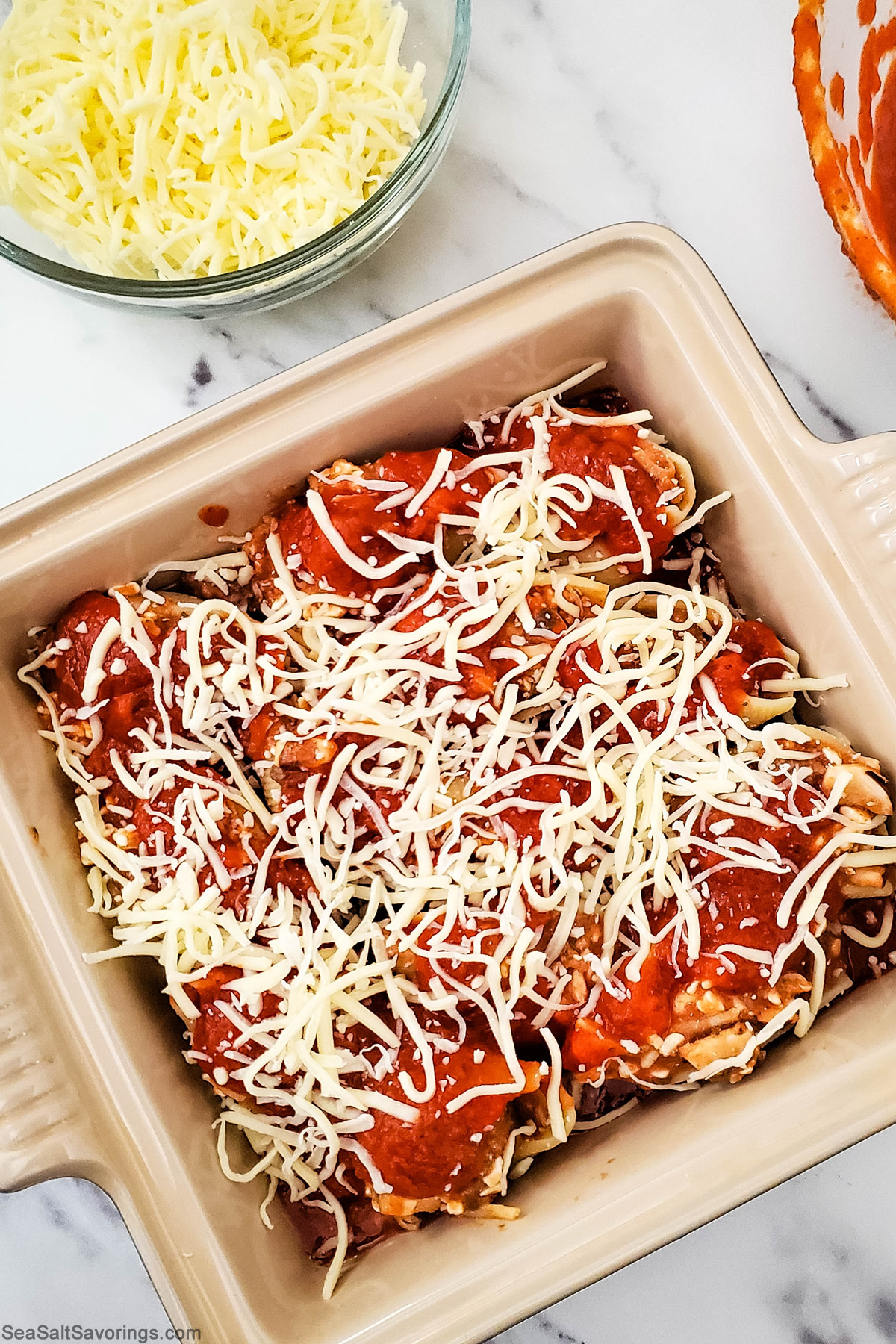 baking dish of stuffed pasta shells with cheese and extra sauce added on top