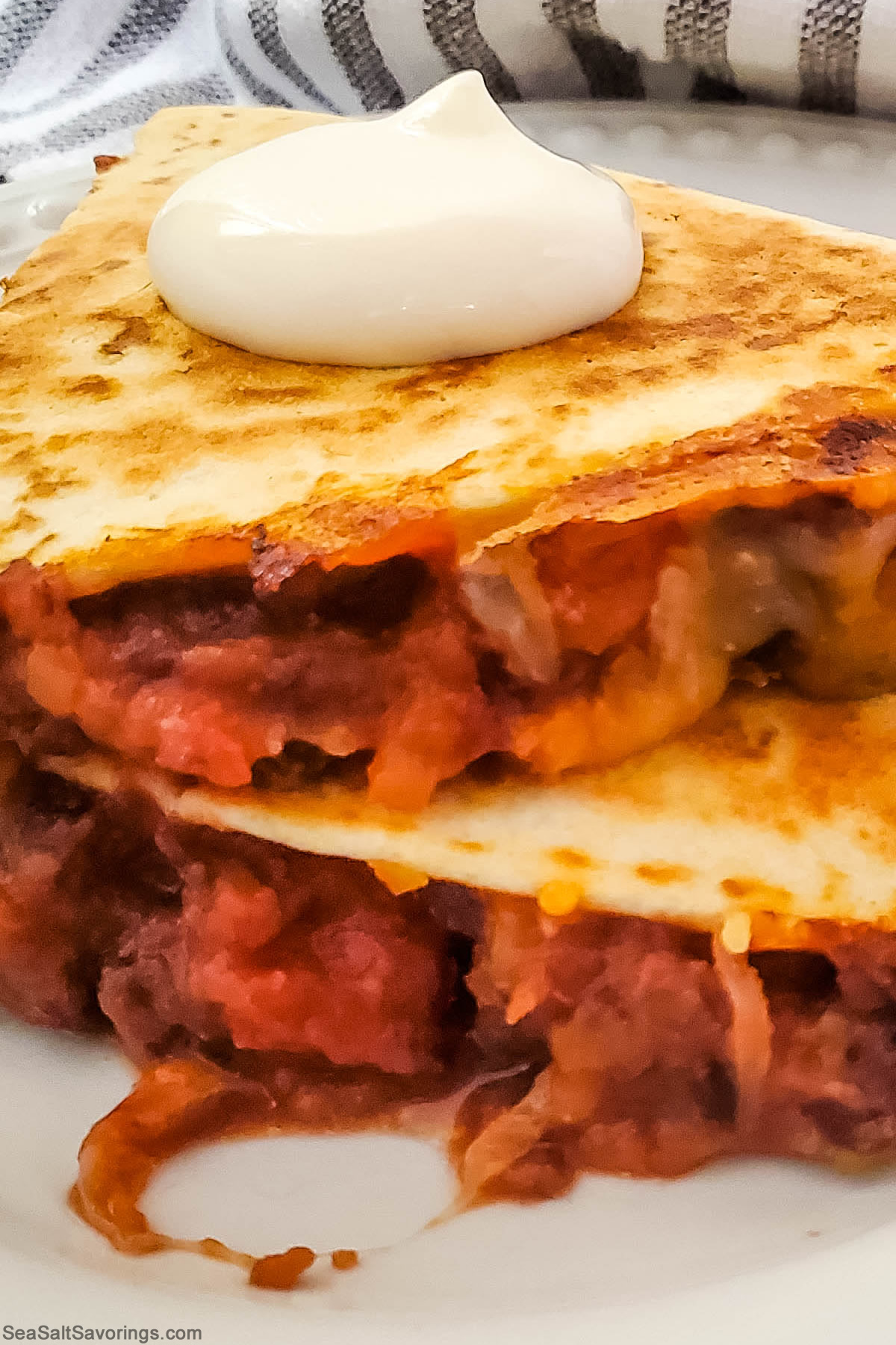 close up view of black bean quesadilla with dollop of sour cream on top