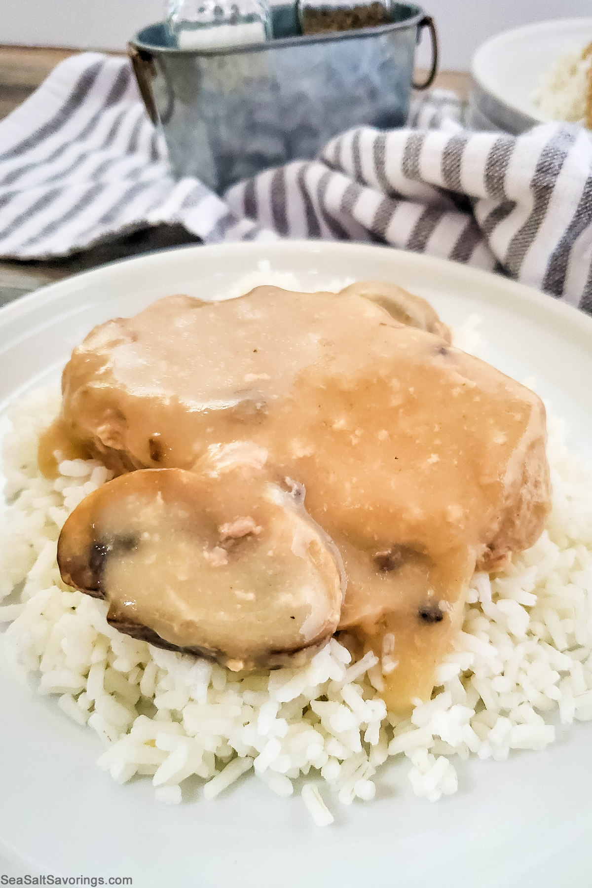 plate of white rice topped with pork chop and mushroom covered in sauce