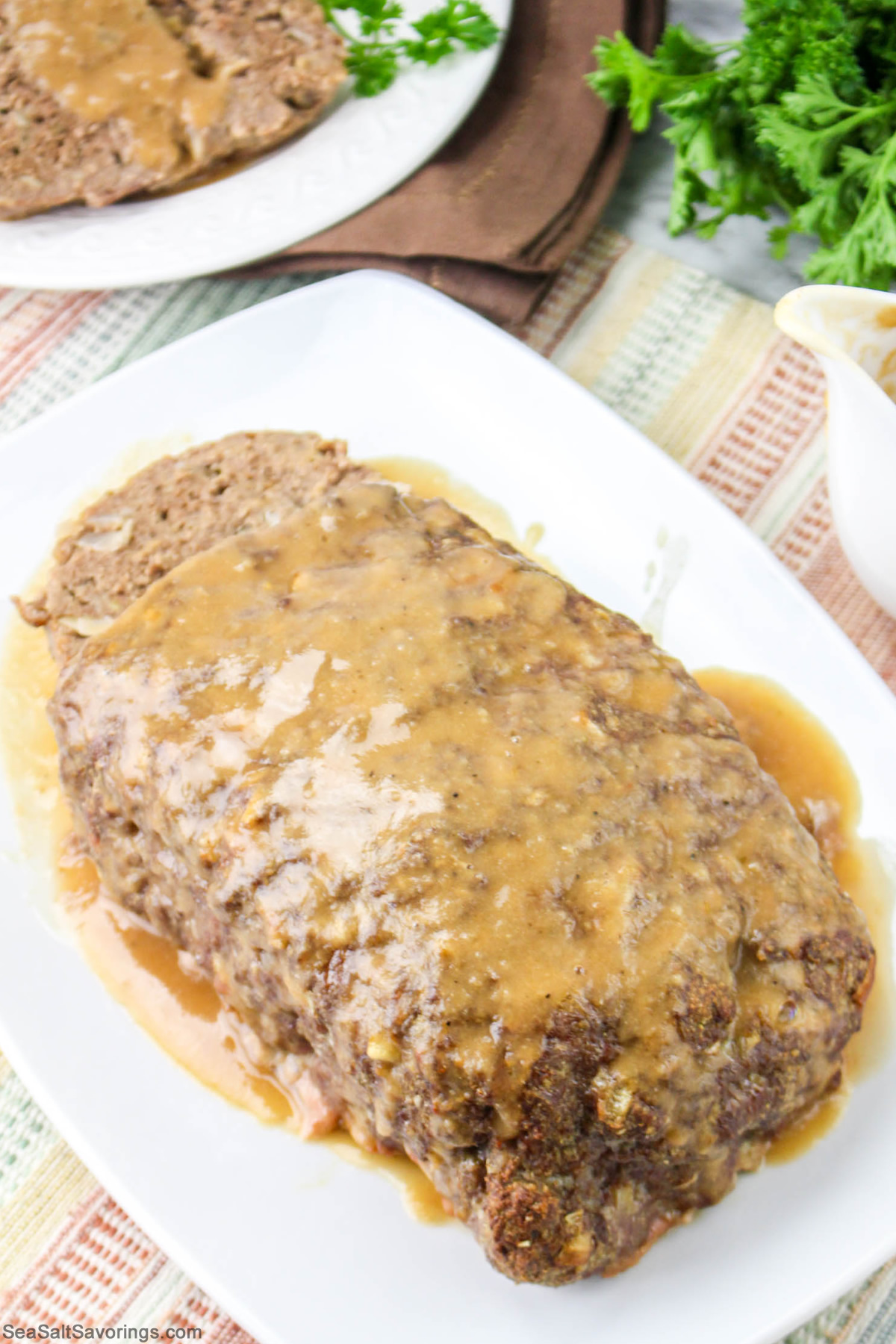 meatloaf on a plate and drenched in brown gravy